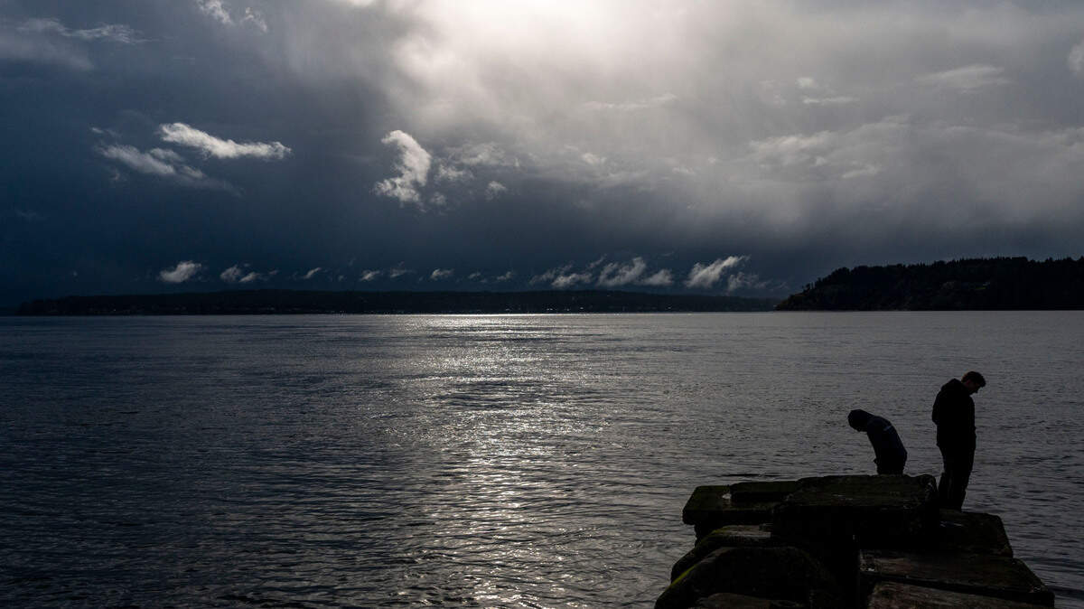 A storm begins to form over Fox Island as Landon Warren (left), of Indianapolis, and Gavin Malloy, of Parkland, look into the waters of the Puget Sound near Titlow Beach in University Place, Wash., on Tuesday, April 12, 2022.