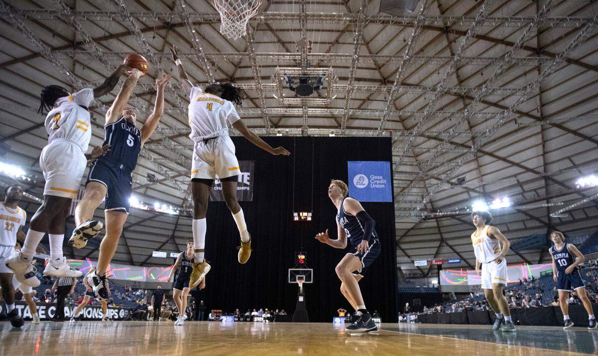Olympia’s Mason Juergens flies to the hoop between Mariner defenders Tijan Saine (left) and Mohamad Camara during Wednesday afternoon’s opening-round game of the WIAA 4A Boys Basketball State Championships tournament in the Tacoma Dome in Tacoma, Washington, on Wednesday, March 2, 2022. Olympia won the game, 50-41.