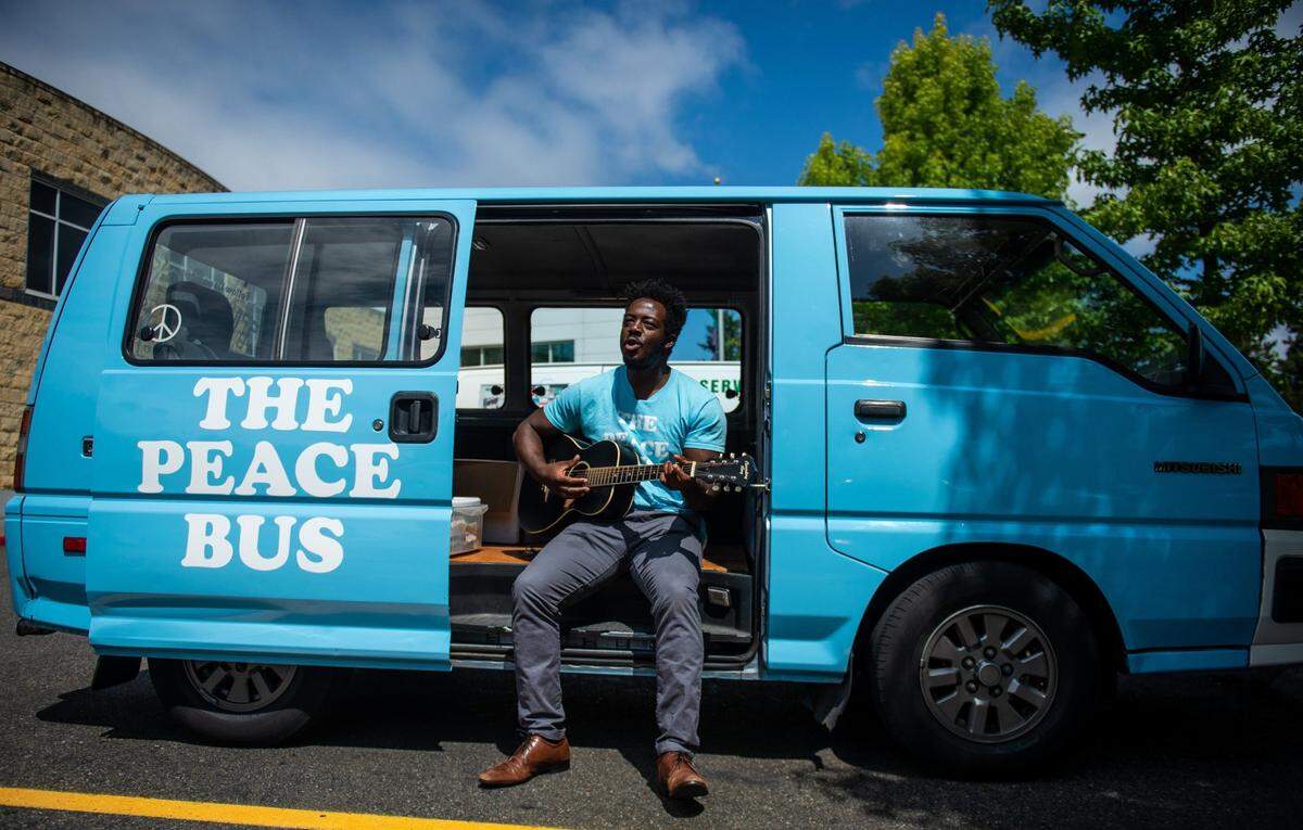 Kwabi Amoah-Forson, founder and president of The Peace Bus, plays guitar from inside the Peace Bus in Tacoma, Wash., on Tuesday, July 30, 2019.