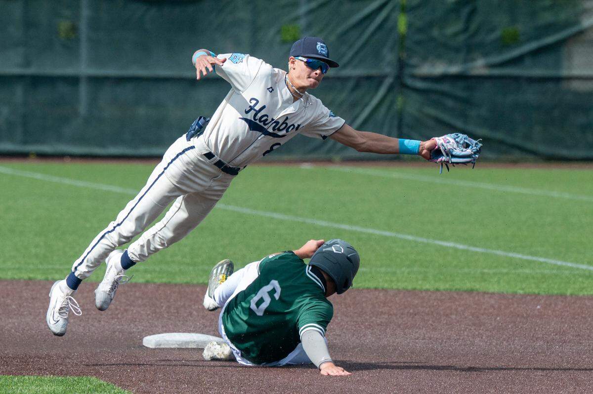 Gig Harbor’s Jayce Corley, left, jumps over Peninsula’s Kainoa Coit to catch the ball as Coit slides into second base on Saturday, May 17, 2025, during the 3A District Championship game in Auburn, Wash.