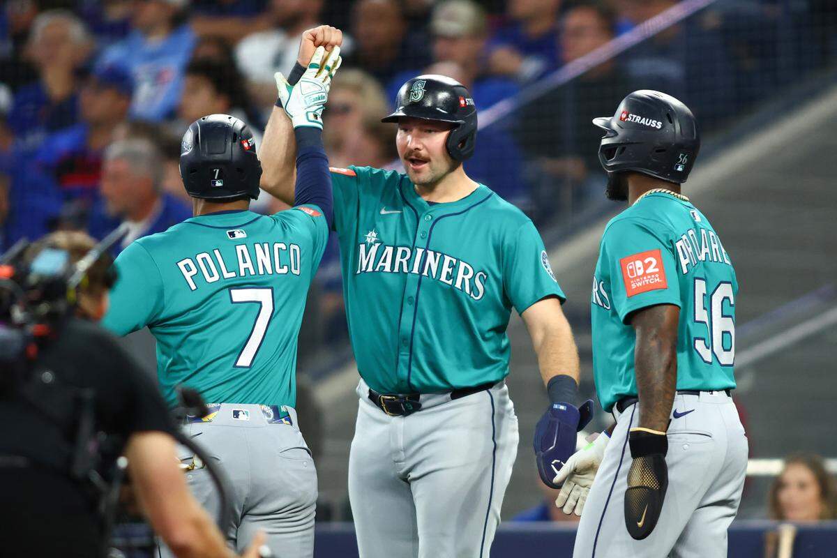 TORONTO, ONTARIO - OCTOBER 13: Jorge Polanco #7 of the Seattle Mariners celebrates with teammates Cal Raleigh #29 and Randy Arozarena #56 after hitting a three run home run against the Toronto Blue Jays during the fifth inning in game two of the American League Championship Series at Rogers Centre on October 13, 2025 in Toronto, Ontario. (Photo by Cole Burston/Getty Images)