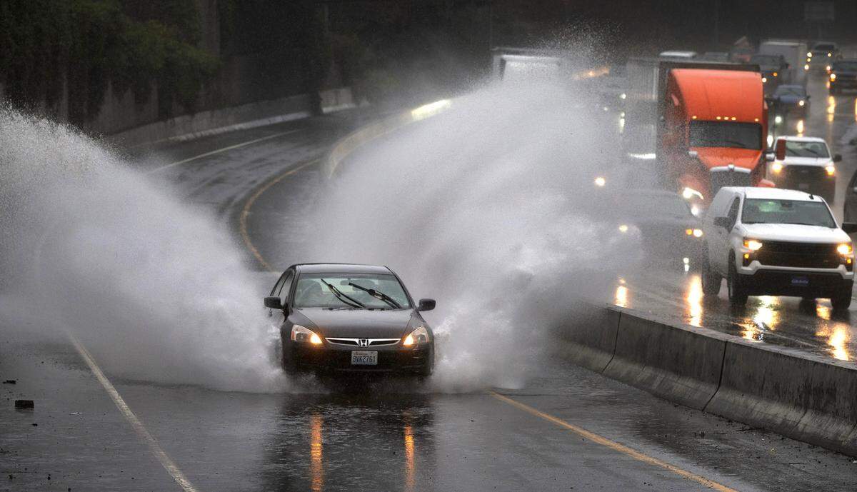 A car plows through standing water on the Washington State Capitol exit off Interstate 5 in Olympia, Washington, on Wednesday, Feb. 28, 2024.