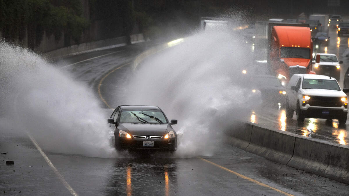 A car plows through standing water on the Washington State Capitol exit off Interstate 5 in Olympia, Washington, on Wednesday, Feb. 28, 2024.