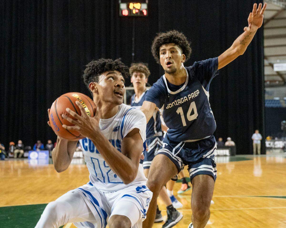 Curtis guard Cinque Maxwell (12) prepares to put up a shot under the basket as Gonzaga Prep forward Jayden Stevens (14) gets back on defense during the first quarter of a Class 4A quarterfinal state tournament game on Thursday, March 3, 2022, at the Tacoma Dome, in Tacoma, Wash.