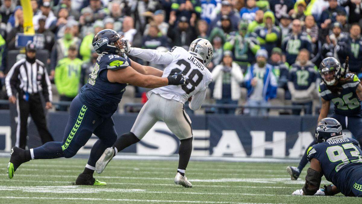 Las Vegas Raiders running back Josh Jacobs (28) stiff arms Seattle Seahawks defensive tackle Al Woods (99) on his way to a rushing touchdown in the second quarter of an NFL game on Sunday, Nov. 27, 2022, at Lumen Field in Seattle.