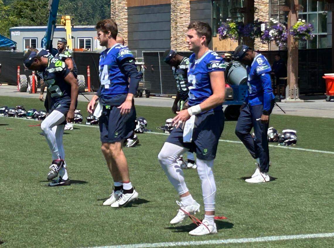 Quarterbacks Sam Darnold (14), Drew Lock (2) and Jalen Milroe (6, right) stretch for the fourth practice of Seahawks voluntary organized team activities (OTAs) June 2, 2025, at the Virginia Mason Athletic Center in Renton.