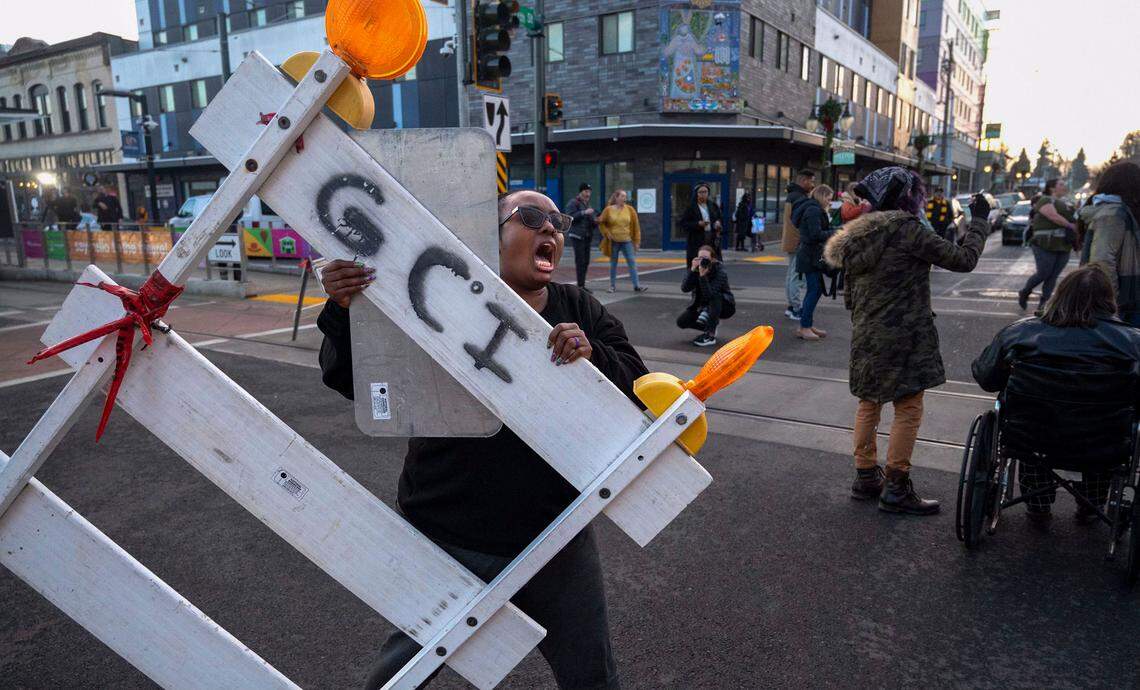 Monet Carter Mixon, the sister of Manuel Ellis, grabs a road block to stop traffic at the intersection of Martin Luther King Way and 11th Street in the Hilltop neighborhood of Tacoma, Wash., after three Tacoma Police officers were found not guilty in the death of Ellis on Thursday, Dec. 21, 2023.