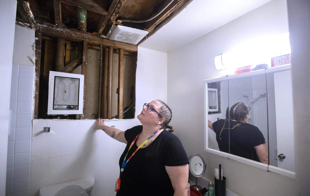 Cassie Morrone shows the water damage in the ceiling and walls of her bathrooms and kitchen in the first-floor apartment where she lives with her husband and children at the Legacy Park Apartments in Lakewood, Washington, on Wednesday, Nov. 8, 2023.