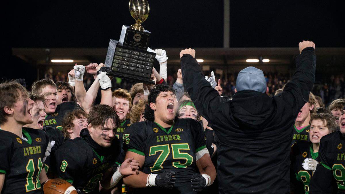 Lynden’s Jesus Ortiz (75) and his Lion teammates celebrate with their state championship trophy following the Lions’ 31-24 victory over the North Kitsap Vikings during the 2A football state championship game at Sparks Stadium in Puyallup, Washington, on Saturday, Dec. 3, 2022.