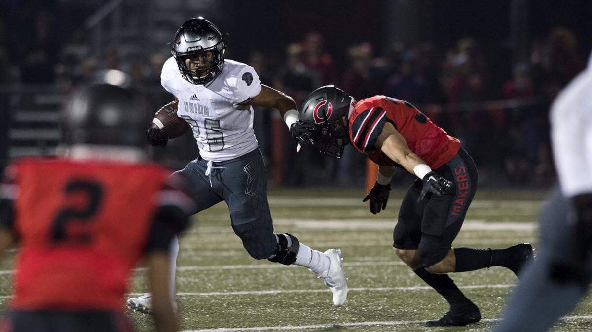 Union’s Joseph Siofele (26) holds off Camas’ Will Schultz (37) during Friday night’s rivalry game at Doc Harris Stadium in Camas on Oct. 27, 2017.