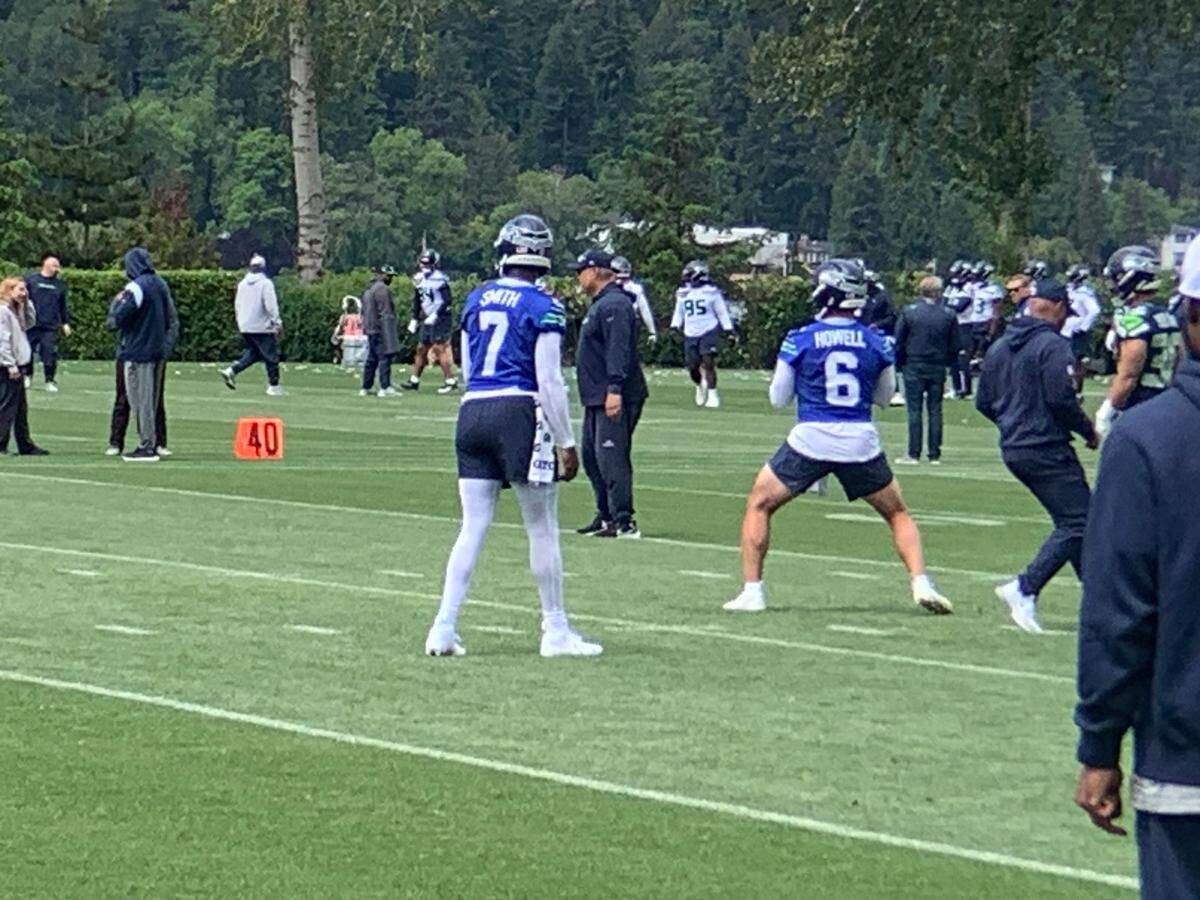 Backup quarterback Sam Howell (6) throws while starter Geno Smith (7) watches as they alternate in drills during the second of 10 NFL organized team activities (OTAs) practices for the Seattle Seahawks at team headquarters in Renton May 23, 2024.