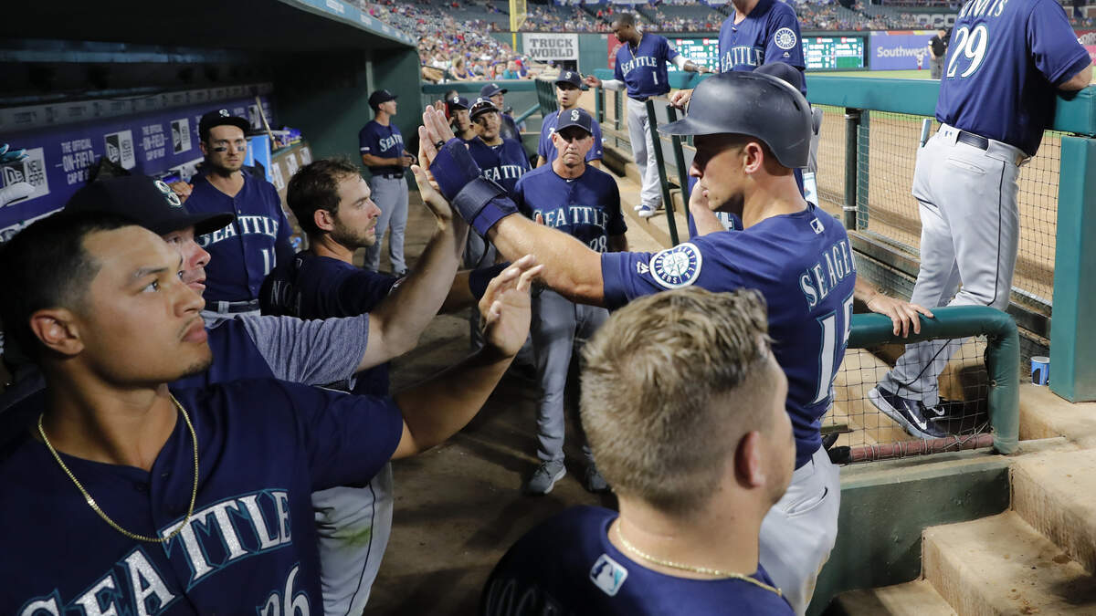 Seattle Mariners’ Kyle Seager, right, is congratulated in the dugout after scoring on a Tom Murphy single during the seventh inning of the team’s baseball game against the Texas Rangers in Arlington, Texas, Tuesday, July 30, 2019.