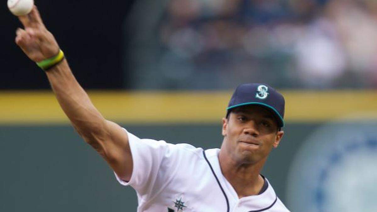 Russell Wilson, throwing out a ceremonial first pitch at a Mariners game at then-Safeco Field in 2013. The Seahawks quarterback says he’s been watching the M’s push to an unlikely playoff spot, and called the Mariners’ latest win Wednesday “an amazing game.”