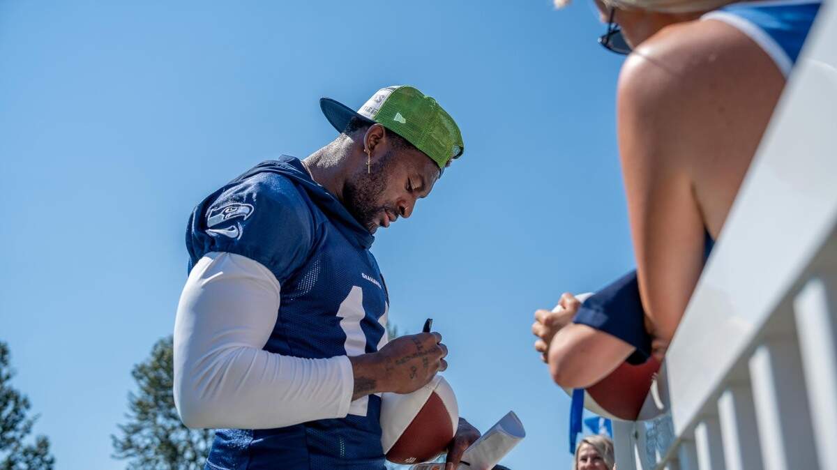 Seattle Seahawks wide receiver DK Metcalf signs a fan’s football after the second day of Seahawks training camp at the Virginia Mason Athletic Center in Renton, Wash. on July 28, 2022.
