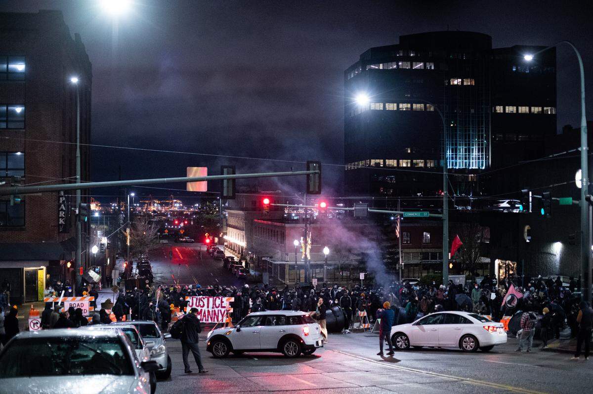 Protesters form a makeshift roadblock near South 9th Street and Commerce Street in Tacoma, Wash., on Sunday, Jan. 24, 2021. Protesters arrived in Tacoma following videos on social media the night before of a Tacoma police officer driving through a crowd of people at a street race.