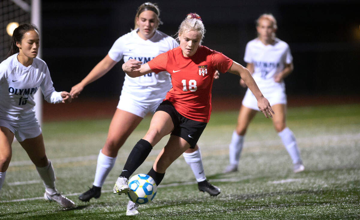 Camas forward Emerson Grafton works the ball against Olympia midfielder Haelynn Kimm (left) and defender Lucy Clarke during Thursday evening’s District 3/4 girls soccer championship game at Ingersoll Stadium in Olympia, Washington, on Nov. 4, 2021. Camas won the game, 3-1.