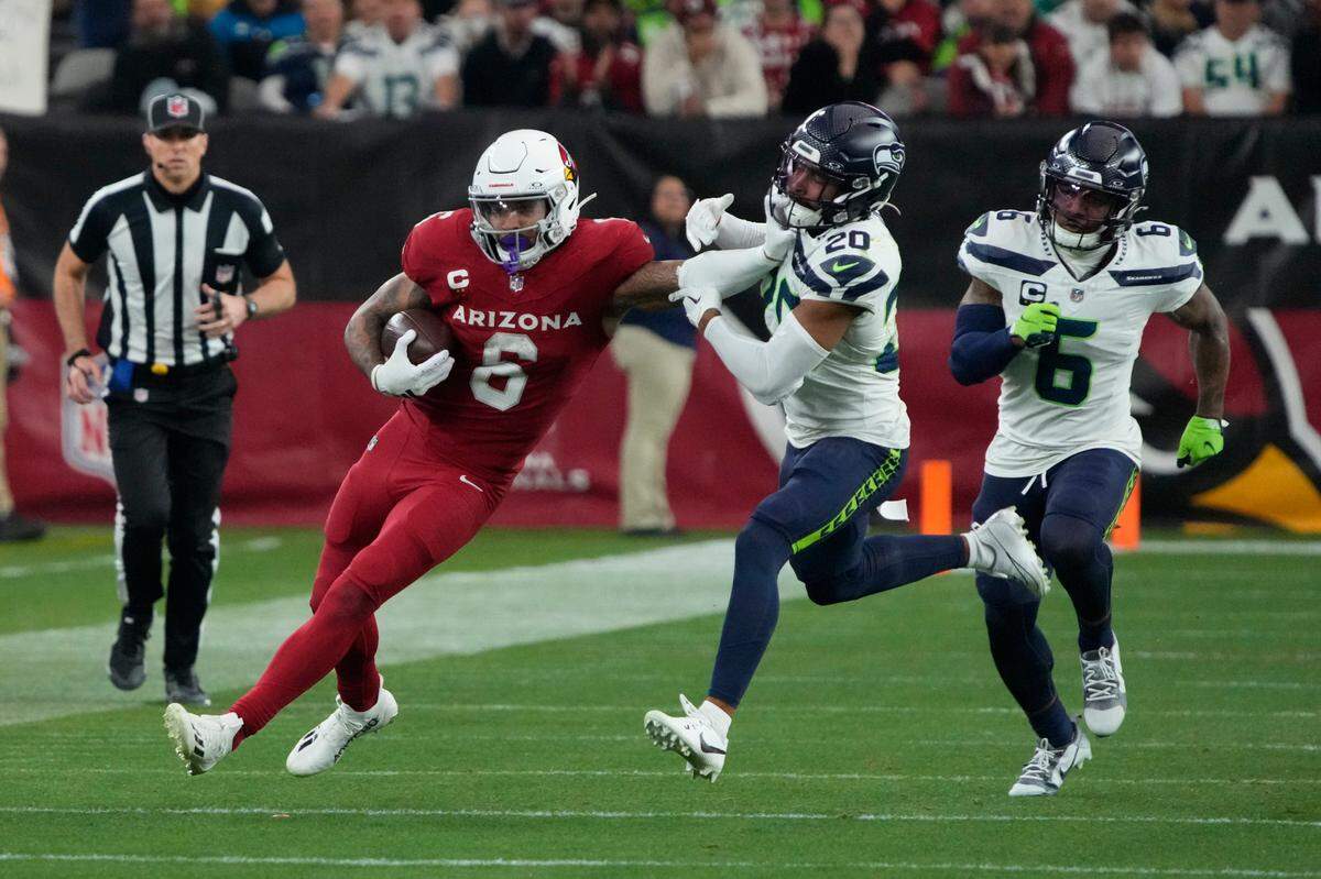 Arizona Cardinals running back James Conner (6) is grabbed by Seattle Seahawks safety Julian Love (20) in the second half of an NFL football game Sunday, Jan. 7, 2024, in Glendale, Ariz. (AP Photo/Rick Scuteri)