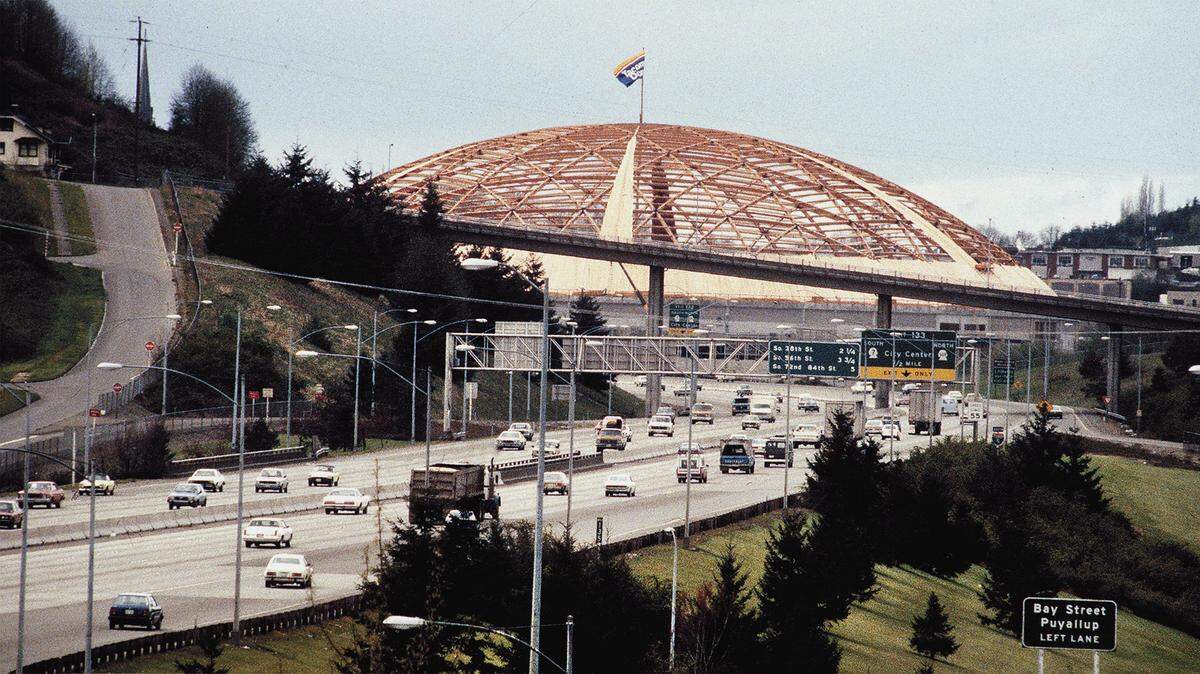 Interstate 5 motorists pass the under construction Tacoma Dome in April 1982 as a plywood skin begins to cover the lattice of beams spanning 530 feet.
