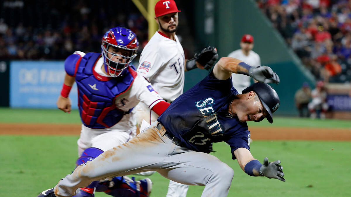 Seattle Mariners’ Dylan Moore is tagged out stealing home by Texas Rangers catcher Jose Trevino, center, as Isiah Kiner-Falefa, rear, looks on in the ninth inning of a baseball game in Arlington, Texas, Saturday Aug. 31, 2019.