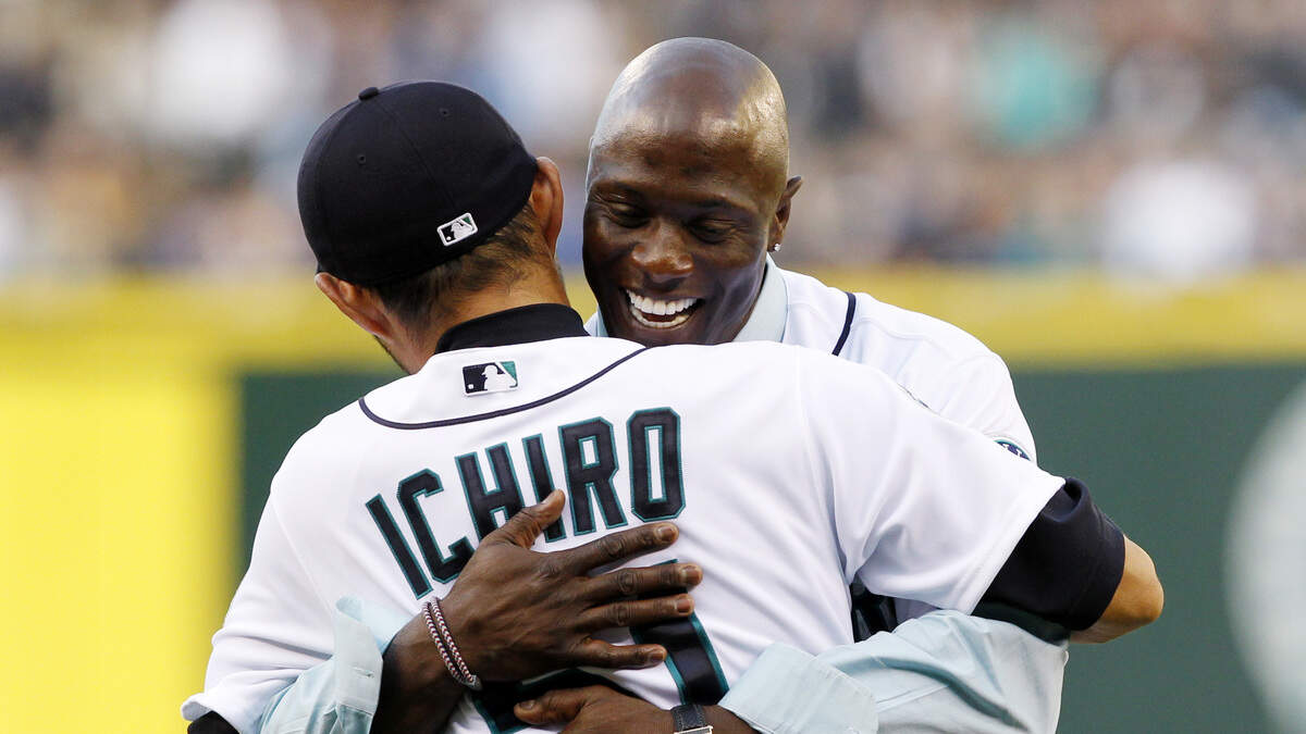 Former Seattle Mariners center fielder Mike Cameron, right, hugs Mariners’ Ichiro Suzuki after Suzuki caught Cameron’s ceremonial first pitch of the Mariners’ home opener MLB baseball game against the Oakland Athletics, Friday, April 13, 2012, in Seattle.