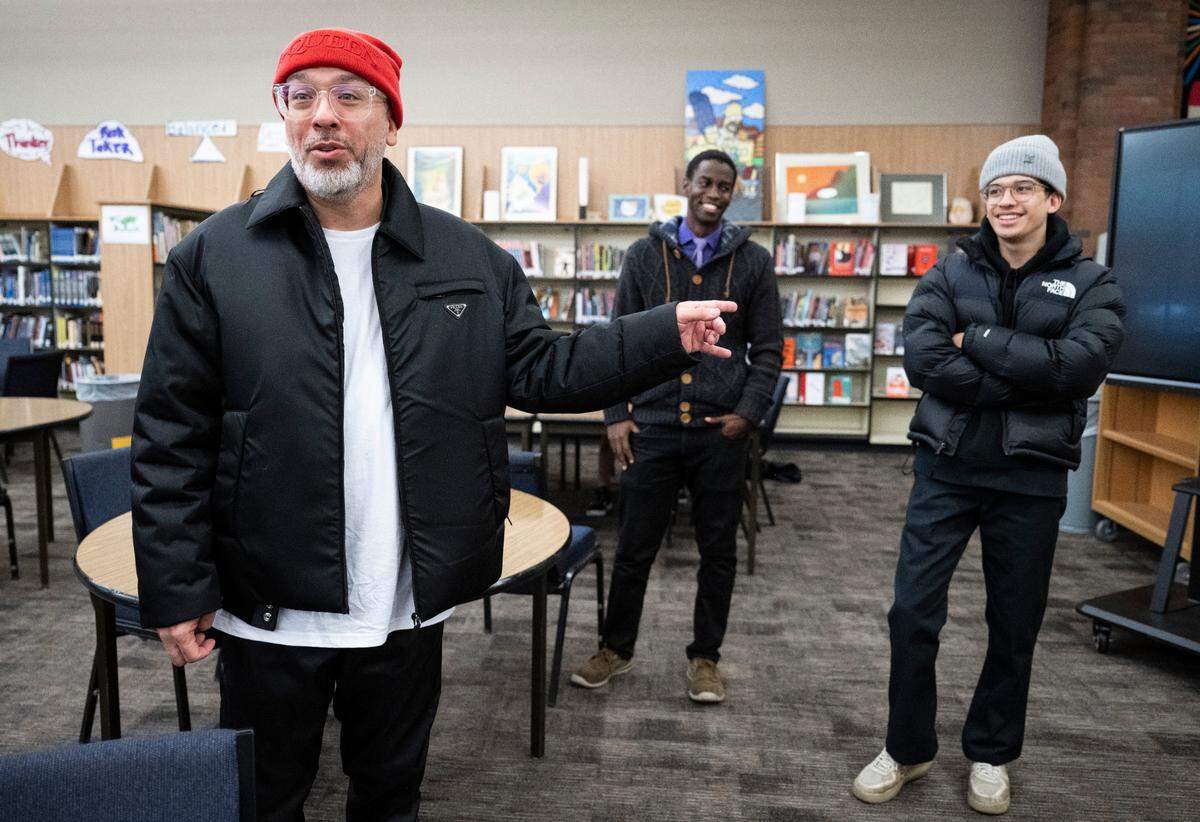 Comedian Jo Koy, left, points to his son Joe Herbert Jr., as they stand in the library during a tour of Koy’s alma mater, Foss High School on Nov. 29, 2022.