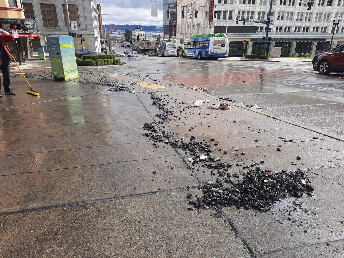 Debris and trash lines the sidewalk along 9th Street on Tuesday in Tacoma. The material was transported down the hill from water used to control a structural fire on Fawcett Avenue.
