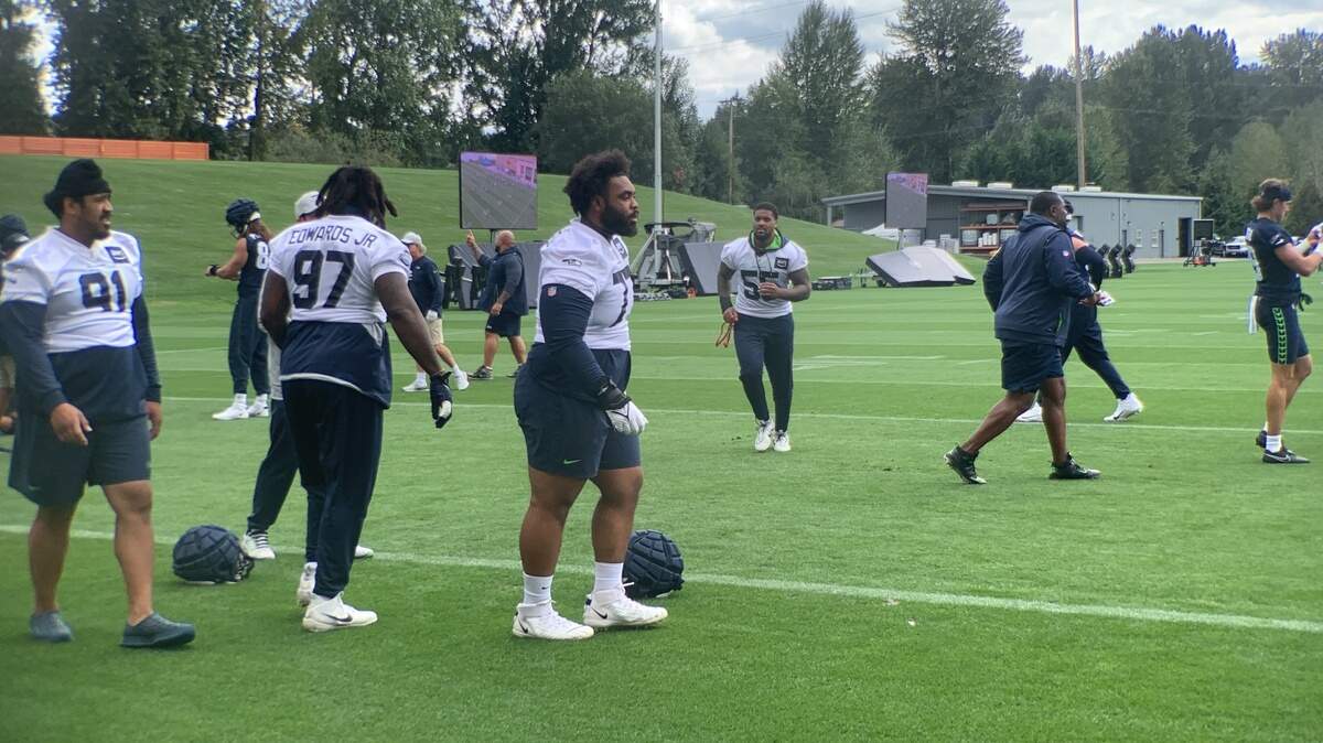 Defensive tackle Matt Gotel (center, helmet at his feet) from Lakes High School next to end Mario Edwards (97) and injured tackle Bryan Mone (91) at the start of Seahawks practice in Renton Aug. 30, 2023. Gotel signed with Seattle’s practice squad the same day.