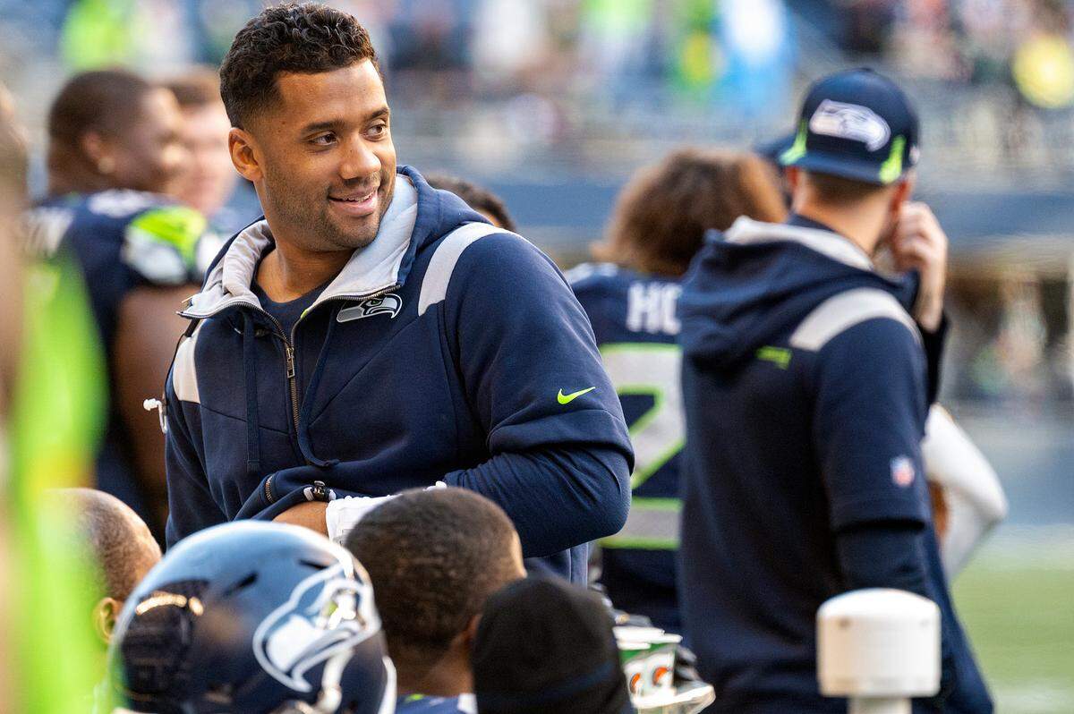 Seattle Seahawks quarterback Russell Wilson smiles while talking with quarterback Geno Smith during the fourth quarter of an NFL game against the Jacksonville Jaguars on Sunday at Lumen Field in Seattle.