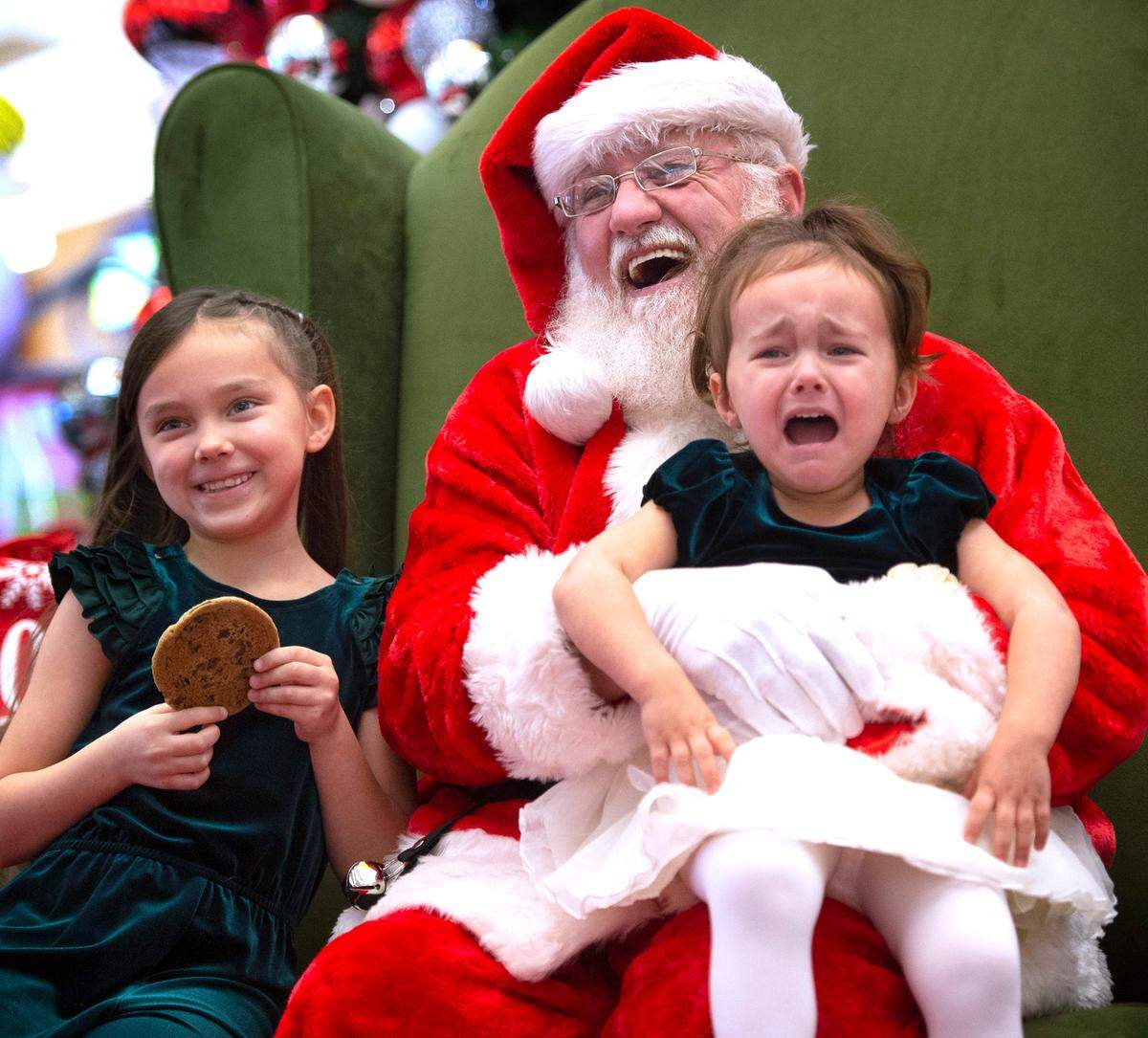 Alana Bushong, 2, of Joint Base Lewis-McChord, expresses her displeasure as she poses for photos with Santa and her sister, LeeLynn Bushong, 6, at the South Hill Mall in Puyallup, Washington, on Wednesday, Nov. 24, 2021.