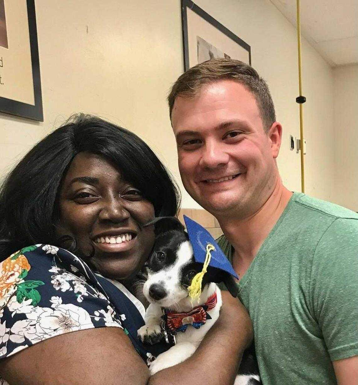 Kenya Jones-Lowell, the head of the Puyallup Planning Commission, poses for a picture with her husband and her 6-year-old Dachshund-terrier mix, Winter Rose, after graduation from a pup training course.