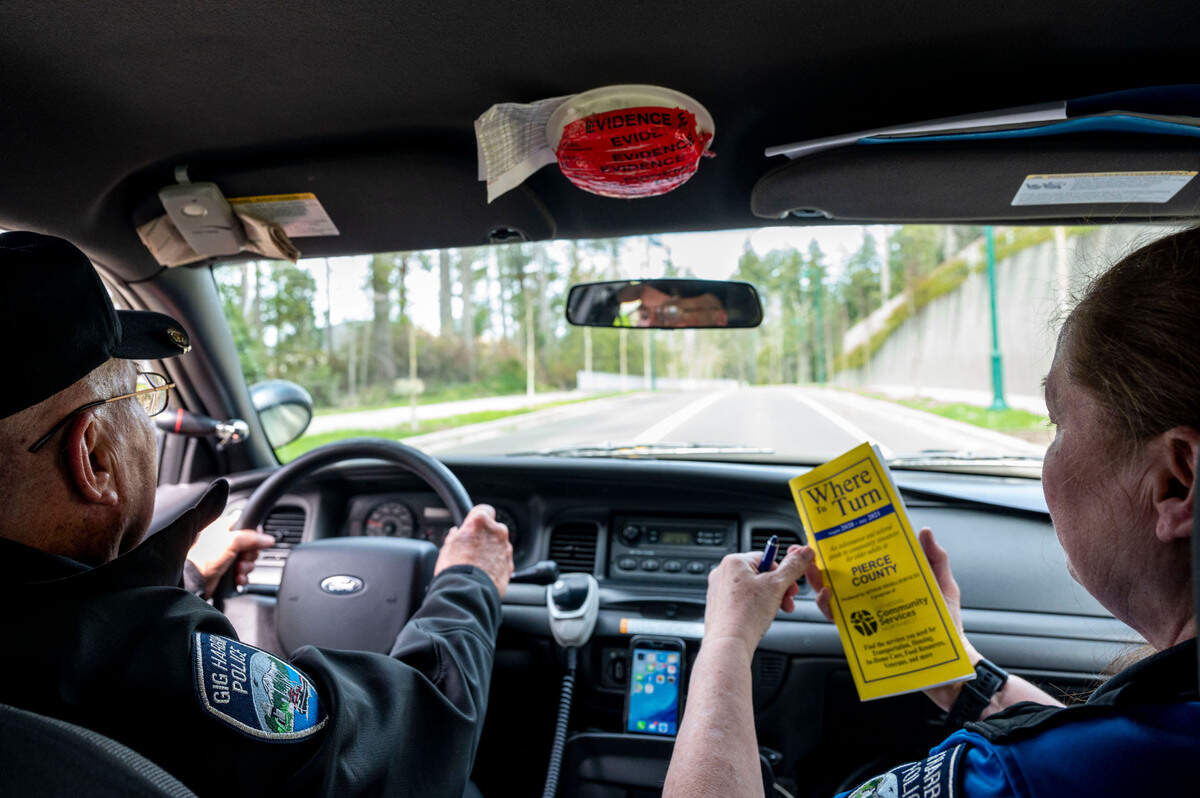 Gig Harbor Police Department volunteers Larry Geringer (left) and Kim Crowder head out in the department’s volunteer patrol car on Wednesday, April 6, 2022, in Gig Harbor, Wash. The duo drove by an elementary school to wave at the students, performed a home check on residents that were out of town and checked on a popular business parking lot to hand out tickets to cars illegally parked cars in disabled spaces.