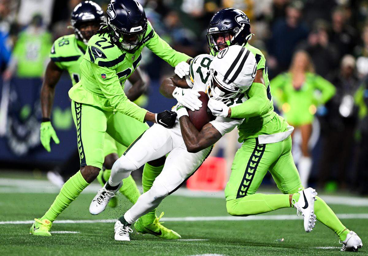 Green Bay Packers wide receiver Romeo Doubs (87) muscles in a touchdown after the reception against Seattle Seahawks safety Julian Love (20) and cornerback Riq Woolen (27) during the first quarter of the game at Lumen Field, on Sunday, Dec. 15, 2024, in Seattle, Wash.
