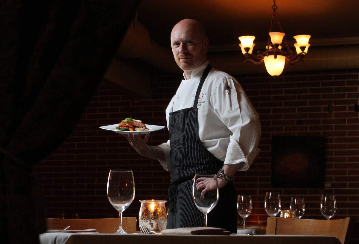 Brix 25 chef and owner Thad Lyman, holds the northwest influenced entree of pan seared king salmon with bacon risotto, peppercress, oven roasted carrot and a hazelnut beurre blanc, in Gig Harbor.
