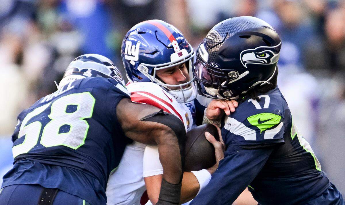 New York Giants quarterback Daniel Jones (8) is wrapped up by Seattle Seahawks linebacker Derick Hall (58) and linebacker Jerome Baker (17) during the third quarter of the game at Lumen Field, on Sunday, Oct. 6, 2024 in Seattle, Wash.