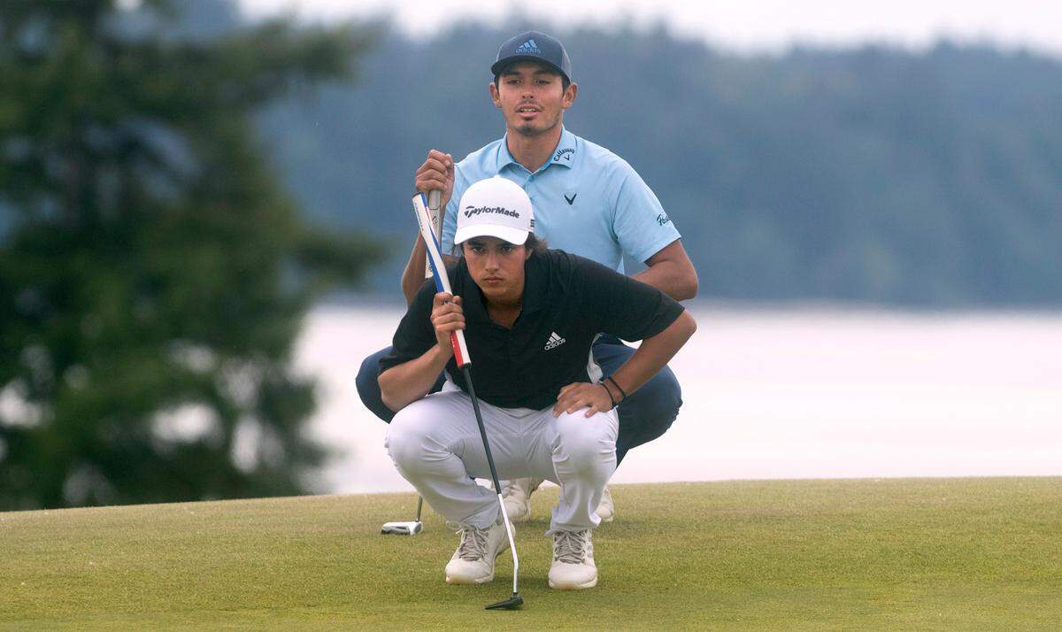Leopoldo Herrera III lines up a putt with the assistance of teammate Kiki Francisco Coelho during the finals match of the USGA Amateur Four Ball Championship at Chambers Bay Golf Course in University Place, Washington, on Wednesday, May 26, 2021.