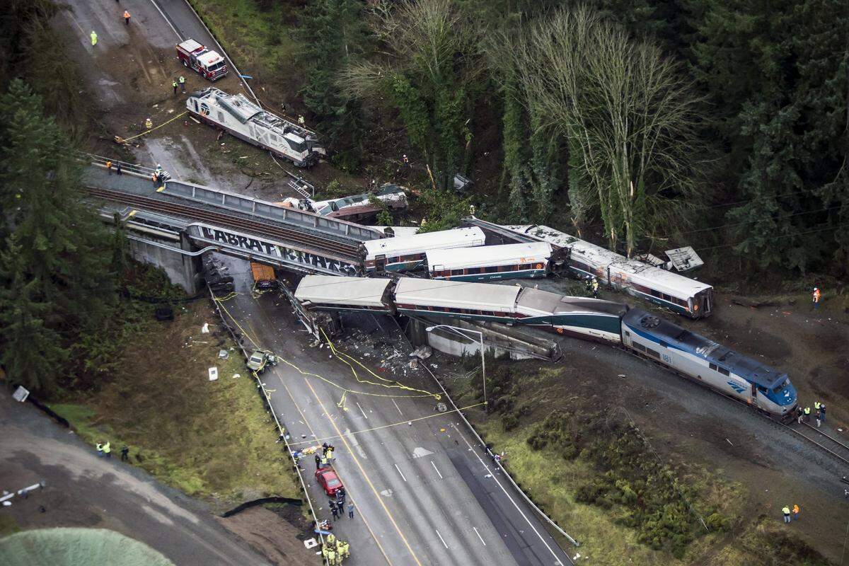 FILE- In this Dec. 18, 2017, file photo, cars from an Amtrak train that derailed lie spilled onto Interstate 5 in DuPont, Wash. Federal investigators say video aboard the Amtrak train that derailed in Washington state shows crews weren’t using personal electronic devices and that the engineer remarked about the speed six seconds before the train went off the tracks south of Seattle. (Bettina Hansen /The Seattle Times via AP, File)