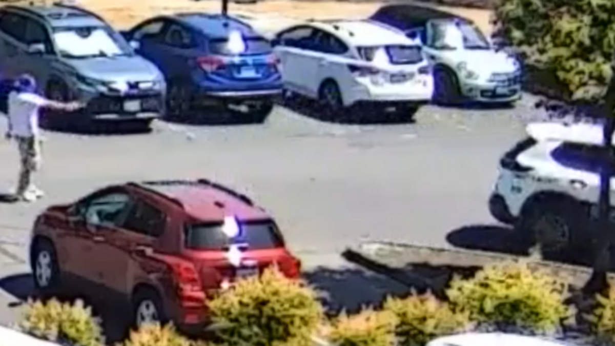 A suspect points a gun at an occupied school patrol officer’s vehicle in the parking lot of the Tacoma Public Schools Office Thursday.