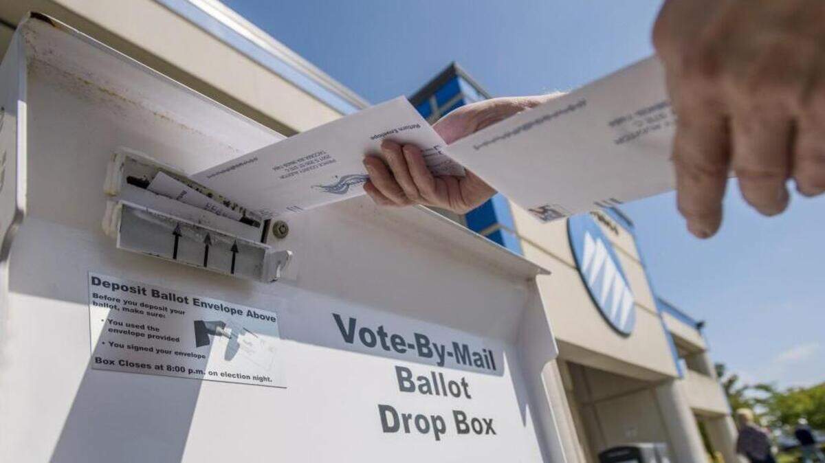 A voter deposits election ballots in the drop box at the Pierce County Annex, Aug. 1, 2016.