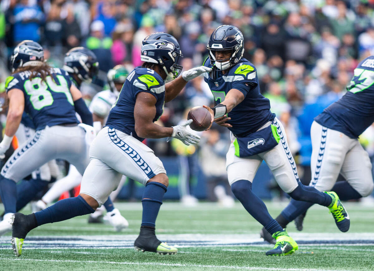 Seattle Seahawks quarterback Geno Smith (7) passes the ball off to Seattle Seahawks running back Kenneth Walker III (9) in the second quarter of an NFL game at Lumen Field in Seattle Wash. on Jan. 1, 2023.