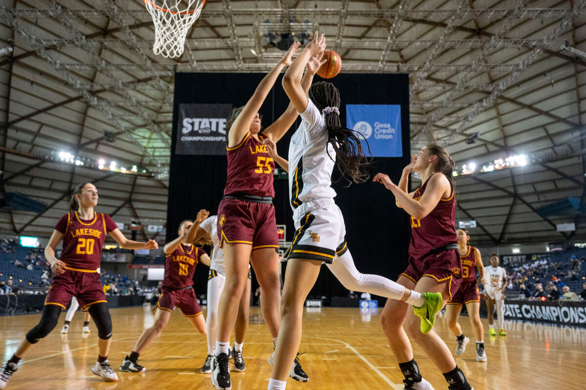 Lincoln guard Ciona Wells (1) attempts to pass off the ball to forward Deandra Woods-Singleton (0) after driving along the baseline as Lakeside center Hannah Dickinson (55) attempts to knock the ball way during the fourth quarter of a Class 3A state tournament game on Wednesday, March 2, 2022, at the Tacoma Dome, in Tacoma, Wash.