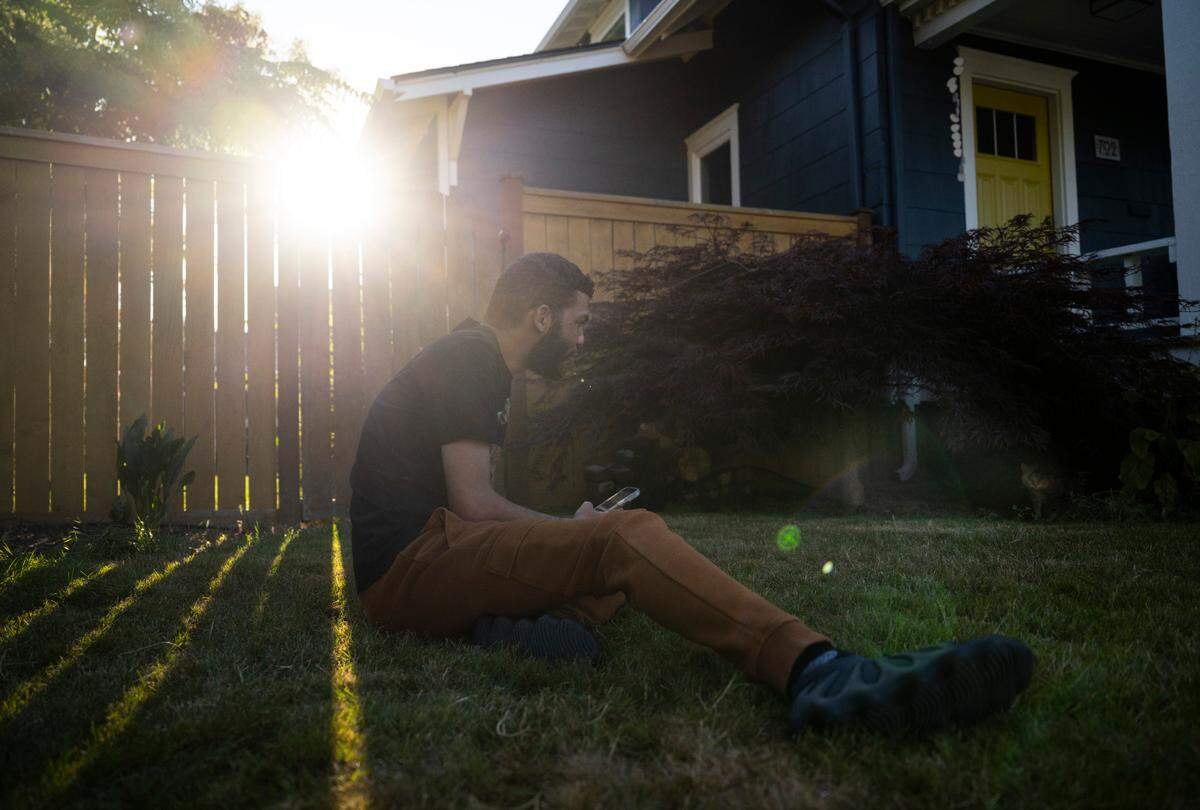 Chris Watson, Tiktoker and founder of the Catluminati, sits in a friend’s yard and tries to coax their cat Bella from underneath a bush on a catwalk in Tacoma, Wash. on August 11, 2022.