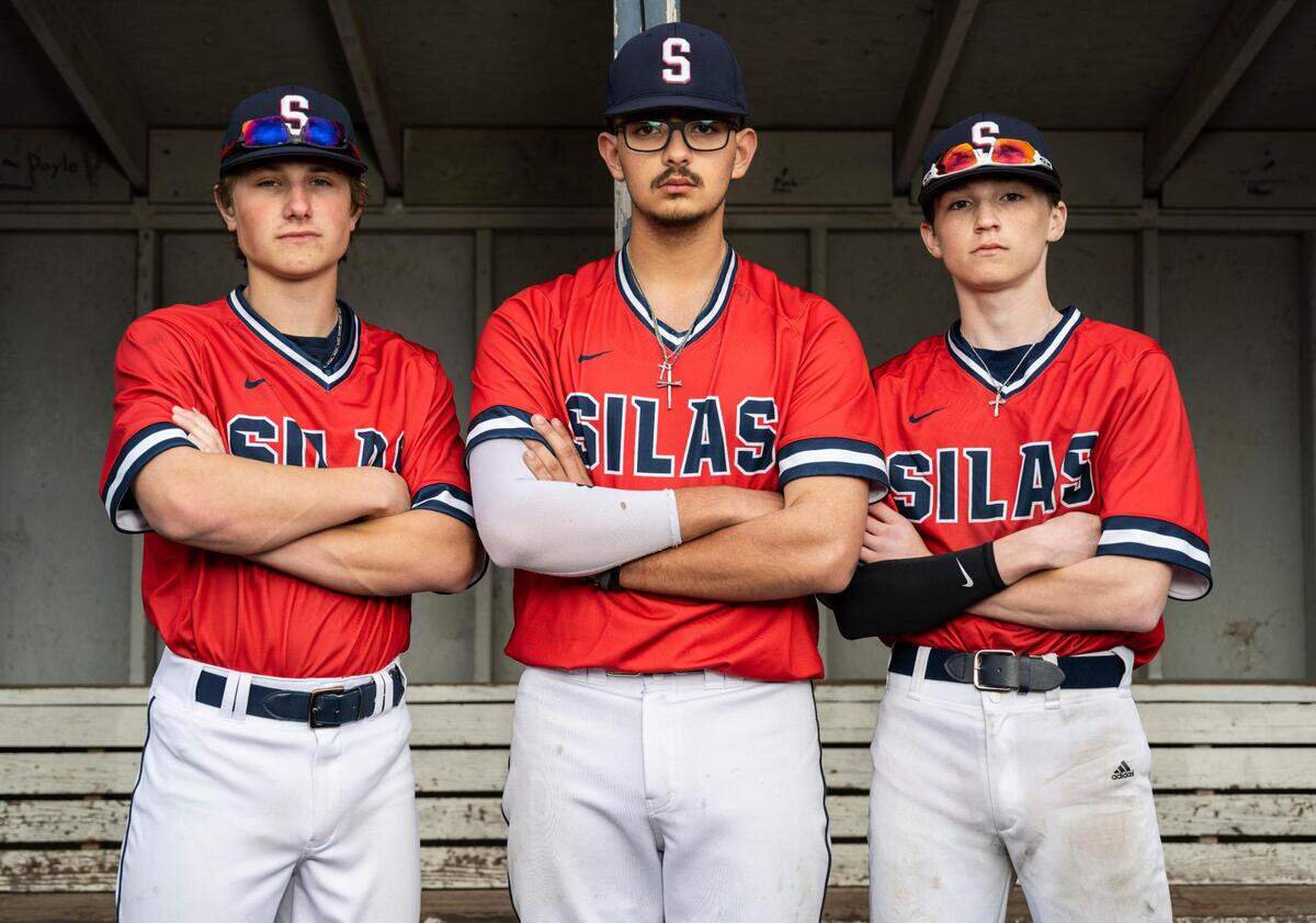 Silas High School varsity baseball players Gavin Yoder, left, Joseph Gutierrez, center, and Nathan Eisenmenger, right, pose for a portrait in the dugout at Silas High School on Thursday, April 21, 2022 in Tacoma, Wash.