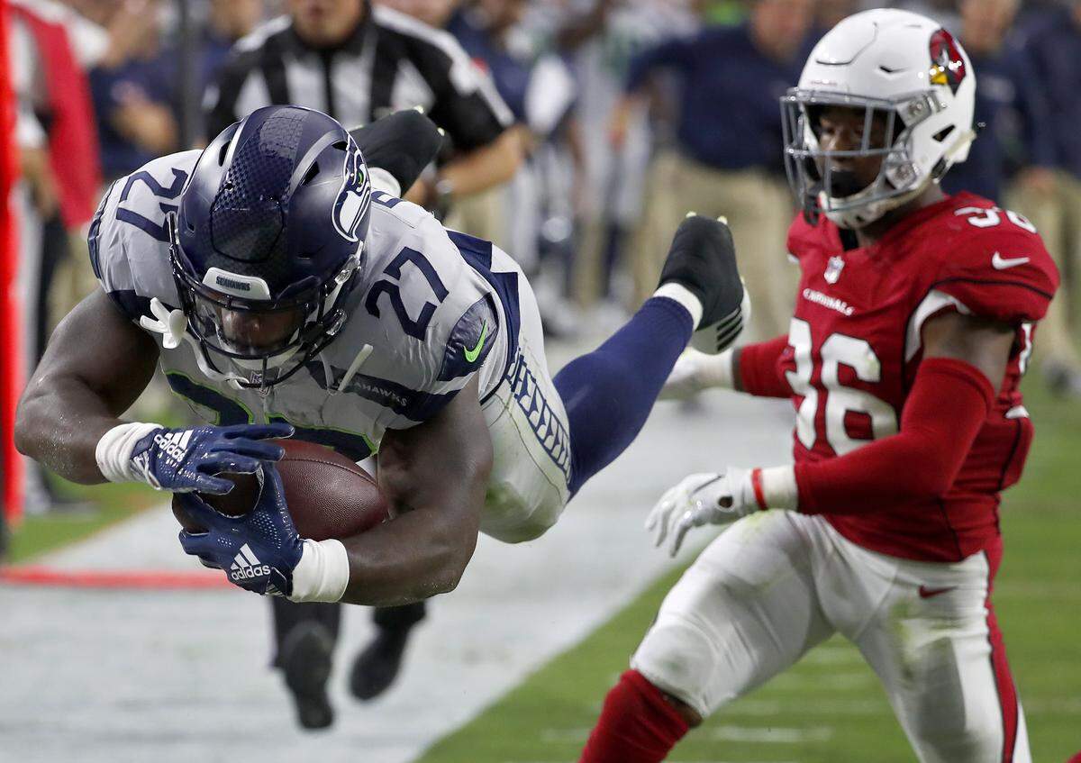 Seahawks running back Mike Davis (27) dives in for a touchdown as Arizona Cardinals defensive back Budda Baker (36), the former University of Washington star, defends during the first half Seattle’s 20-17 win Sunday. Davis rushed for a career-high 101 yards.