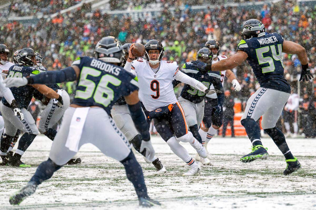 Chicago Bears quarterback Nick Foles (9) attempts to scramble out of the pocket as Seattle Seahawks middle linebacker Bobby Wagner (54) and outside linebacker Jordyn Brooks (56) defend during the first quarter of an NFL game on Sunday afternoon at Lumen Field in Seattle.