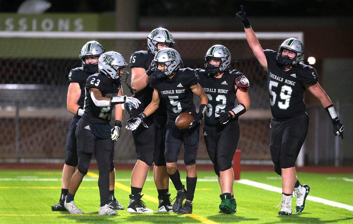 Emerald Ridge running back Tony Harste (5) is congratulated by teammates following his touchdown run during Thursday night’s 4A SPSL football game against the Bellarmine Prep Lions at Sparks Stadium in Puyallup, Washington, on Sept. 30, 2021.