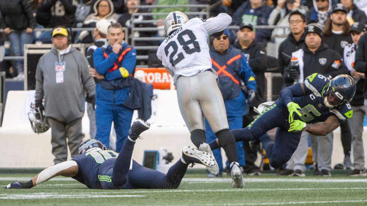 Las Vegas Raiders running back Josh Jacobs (28) runs between Seattle Seahawks linebacker Uchenna Nwosu (10) and safety Quandre Diggs (6) after catching a pass from quarterback Derek Carr (4) during the third quarter of an NFL game on Sunday, Nov. 27, 2022, at Lumen Field in Seattle.