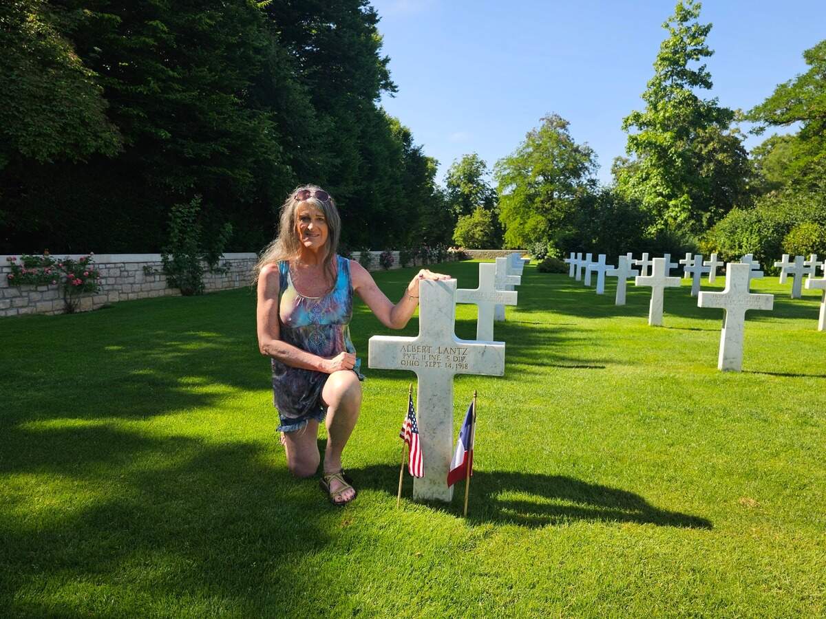 Lynn Goralski sits beside the grave of her first cousin twice removed, Albert Lantz, left, at the St. Mihiel American Cemetery and Memorial in France on Sunday, June 22, 2025.