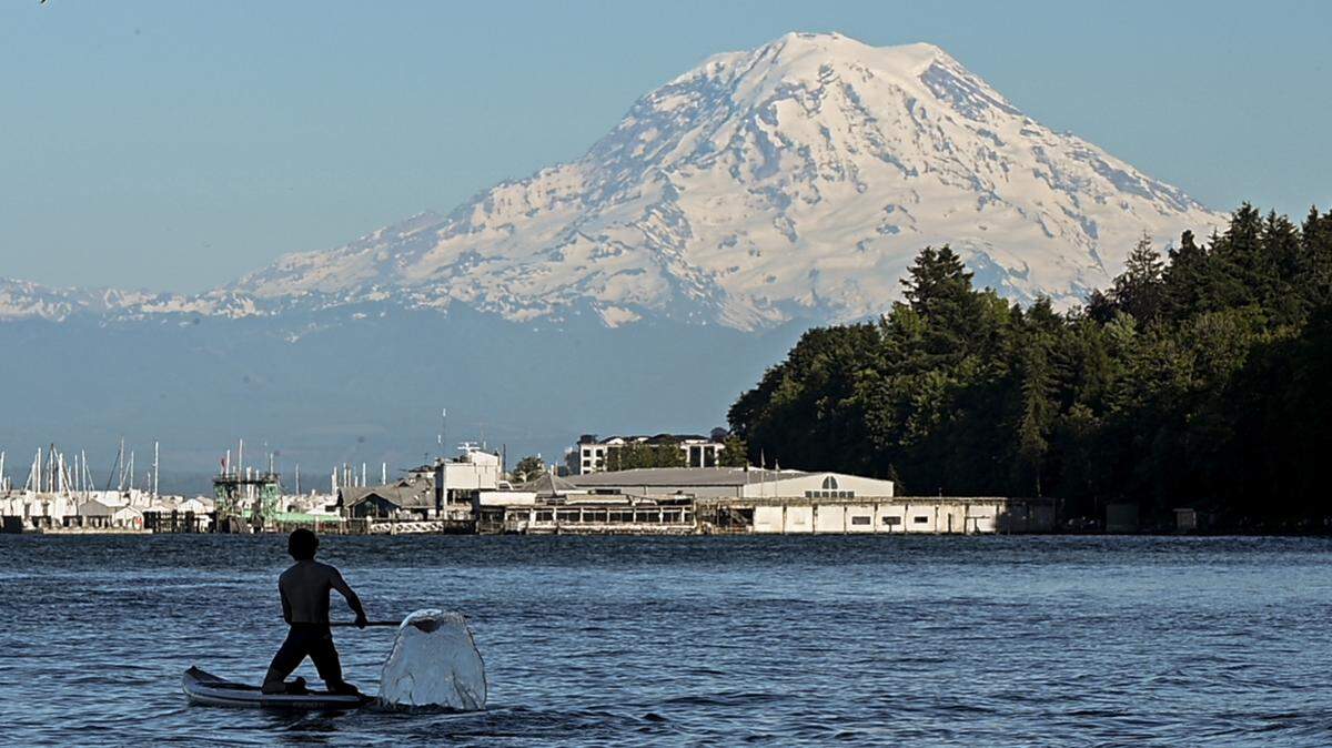 A paddle boarder paddles along the shore, as temperatures rise, at Owens Beach, on Friday, June 7, 2024, in Tacoma, Wash.