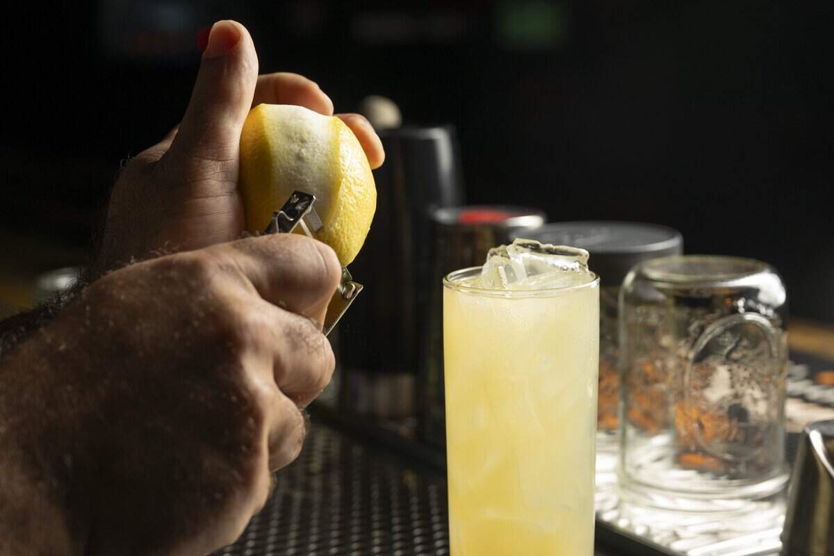 Owner Sam Halhuli peels a lemon to garnish a Randy Buck mule on Wednesday, July 8, 2026, in Tacoma, Wash.