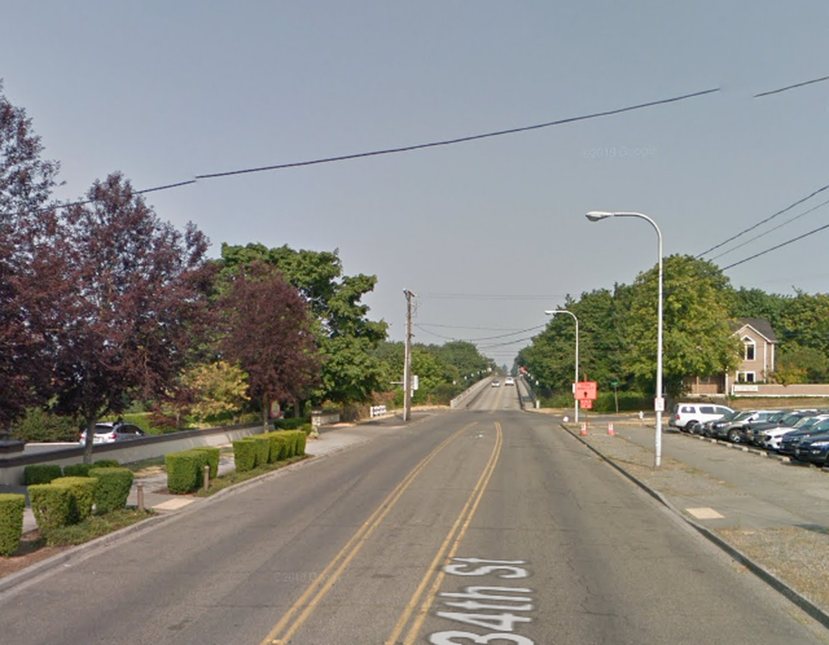 Google Street View depicts East 34th Street in Tacoma in August 2017, with no pedestrian markings on an alleged unmarked crosswalk between two ADA-accessible curb ramps in the foreground.